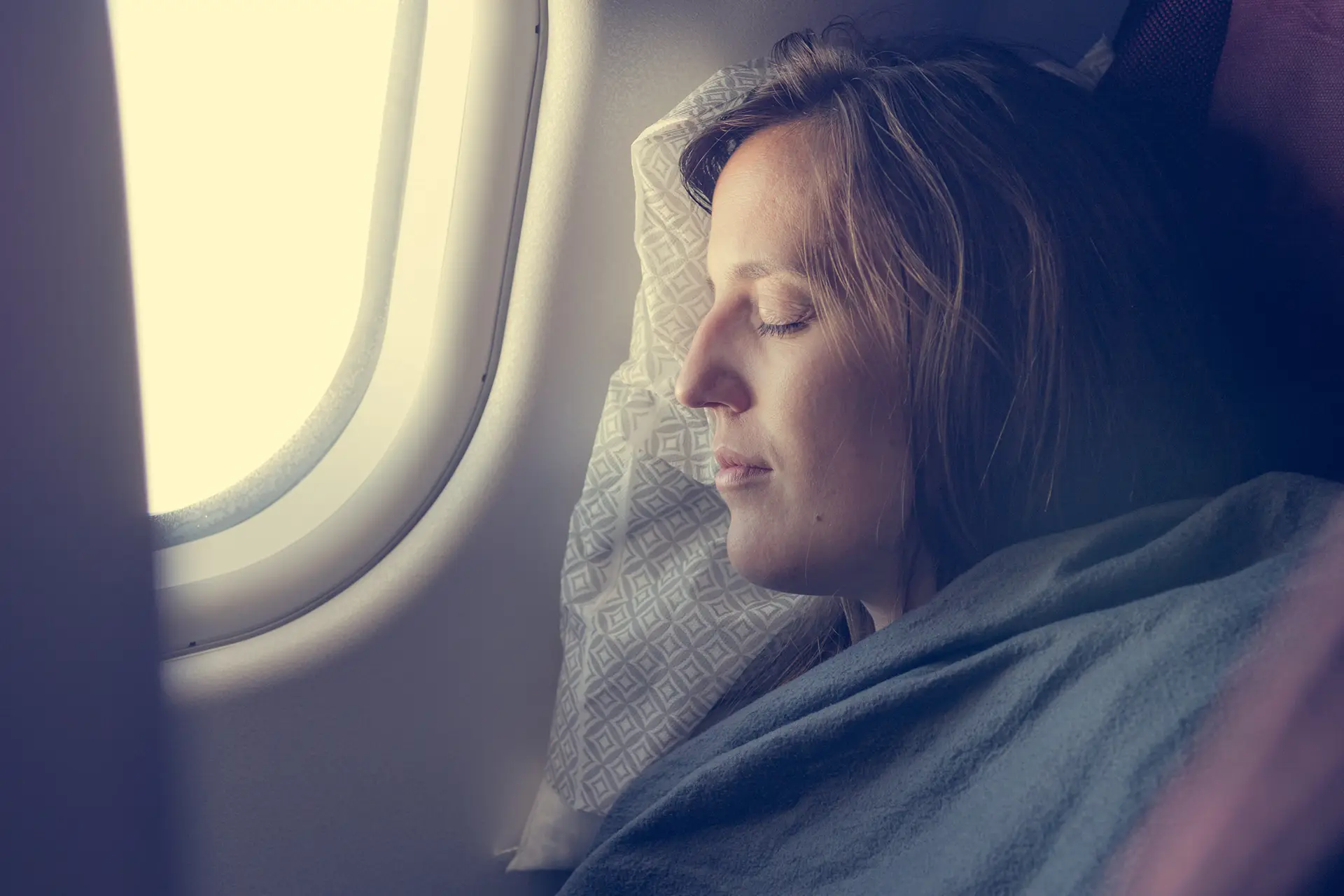 Schlafende Frau im Flugzeug auf Kissen